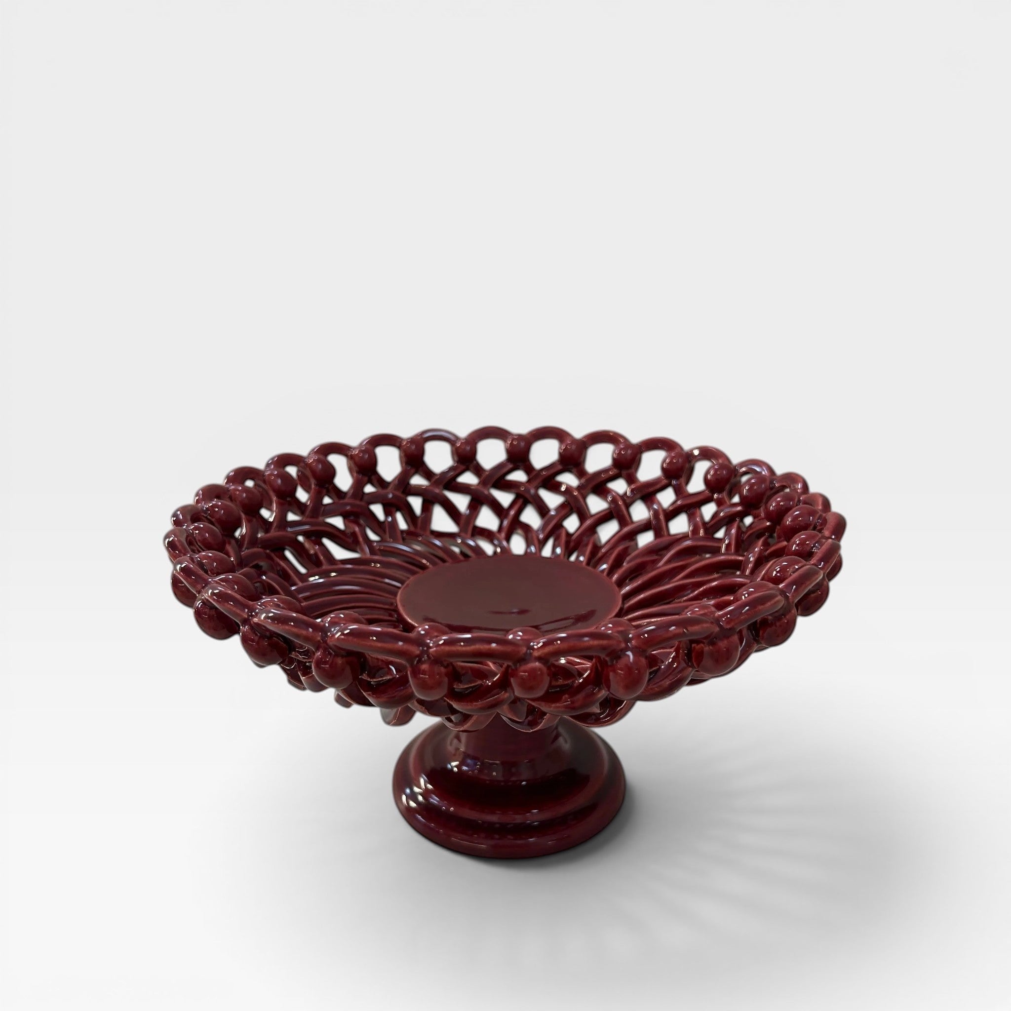 Keep Collections deep red ceramic pedestal fruit bowl with intricate woven detailing.