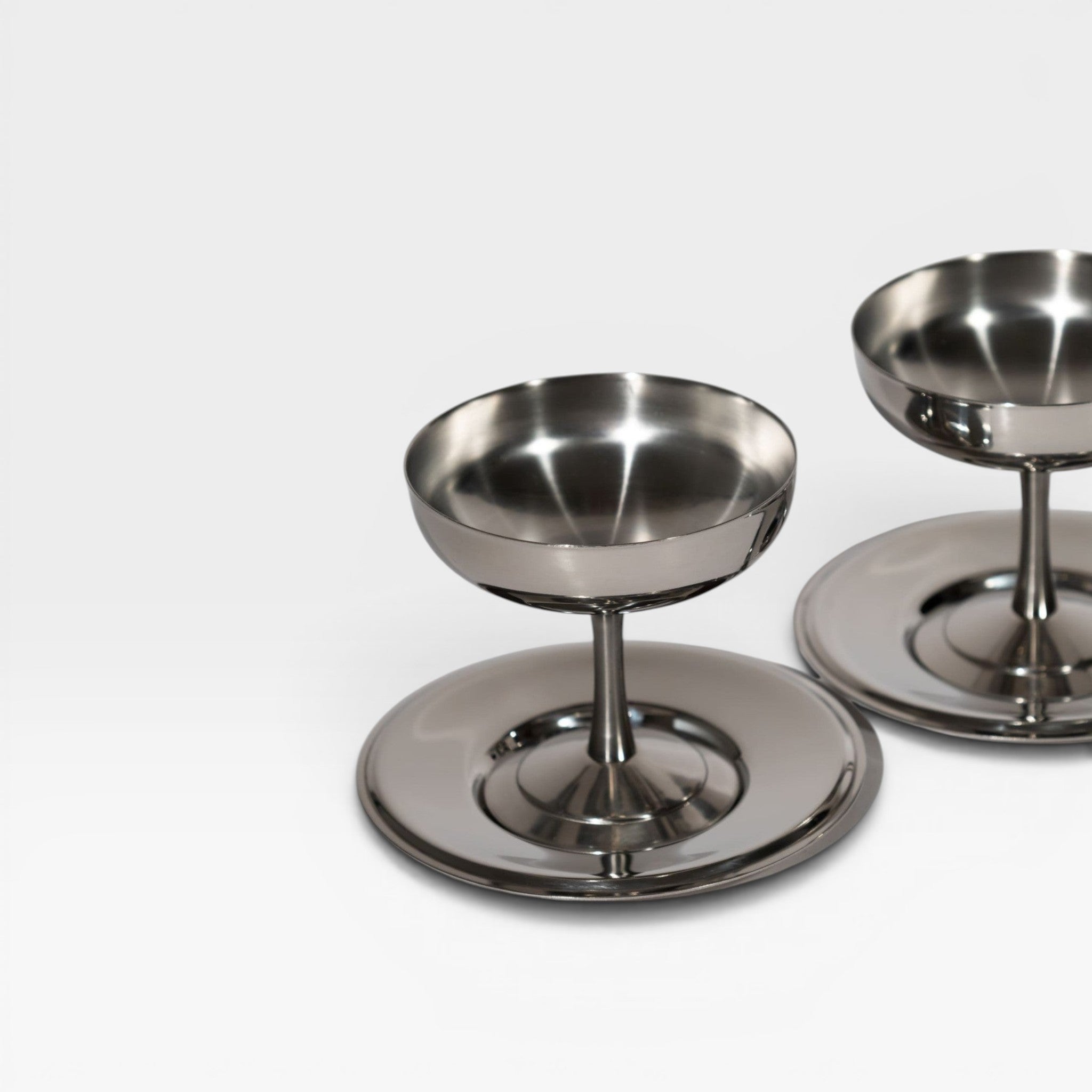 keep-collections stainless steel coupe glasses with a polished metallic finish and pedestal base on a white surface